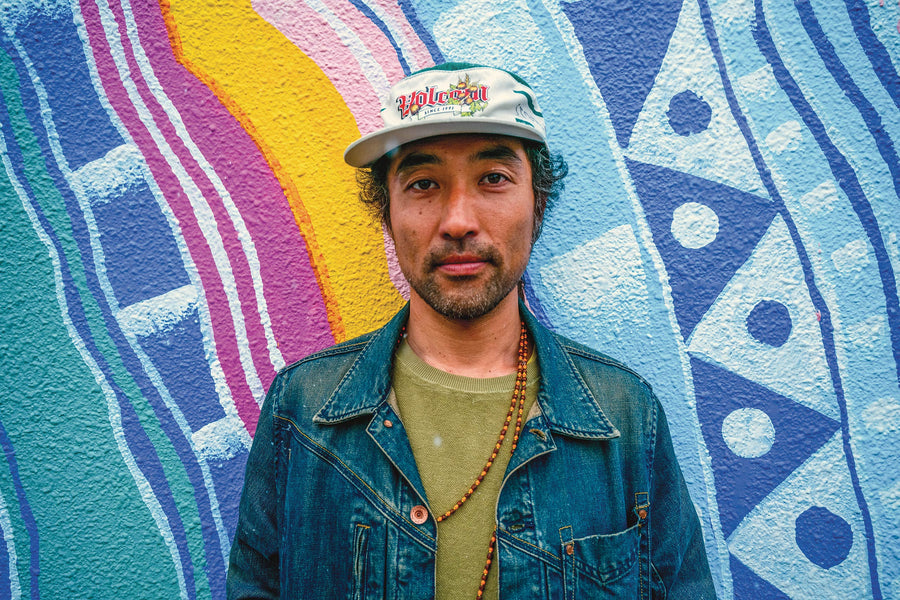 Masashi Nishina (aka ASA3000) stands before an original mural from his 2014 City Art Project initiative in Ōmachi, Japan.  Photo: Alastair Spriggs  